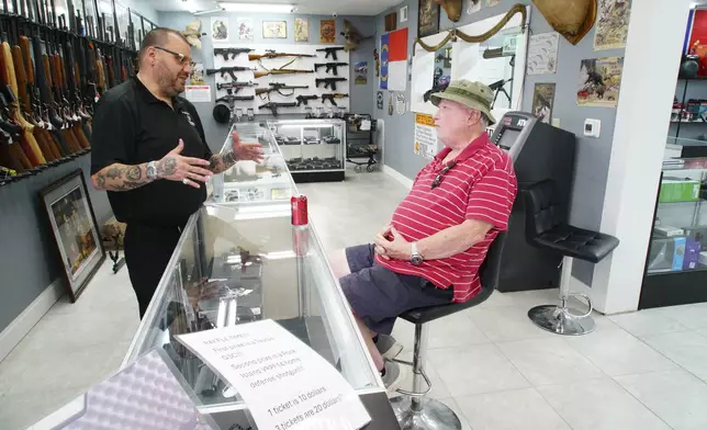 Ralph Rodriguez, left, chats with Army veteran Sidney High at his Fayetteville, N.C., pawn shop. Friday, May 9, 2025. (AP Photo/Allen G. Breed)