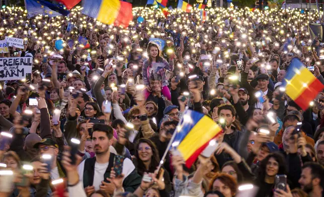 People shine the lights of their mobile phones during an electoral rally of presidential candidate Nicusor Dan, a week ahead of the second round of the country's presidential election redo in Bucharest, Romania, Sunday, May 11, 2025. (AP Photo/Andreea Alexandru)