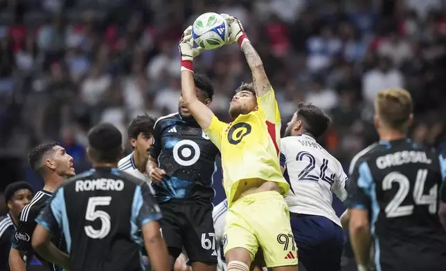 Minnesota United goalkeeper Dayne St. Clair (97) grabs the ball out of the air away from Vancouver Whitecaps' Brian White (24) during the second half of an MLS soccer match in Vancouver, on Wednesday, May 28, 2025. (Darryl Dyck/The Canadian Press via AP)