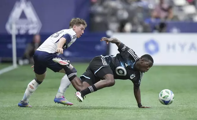 Minnesota United's Bongokuhle Hlongwane, right, stumbles while vying for the ball against Vancouver Whitecaps' Tate Johnson during the first half of an MLS soccer match, in Vancouver, on Wednesday, May 28, 2025. (Darryl Dyck/The Canadian Press via AP)