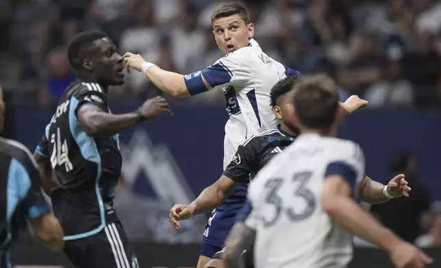 Vancouver Whitecaps' Ranko Veselinovic, back right, watches the ball after using his head to direct the ball on net during the second half of an MLS soccer match against Minnesota United, in Vancouver, on Wednesday, May 28, 2025. (Darryl Dyck/The Canadian Press via AP)