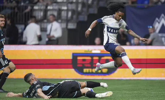 Vancouver Whitecaps' Jayden Nelson, right, leaps over Minnesota United's Michael Boxall as he has the ball taken away during the second half of an MLS soccer match, in Vancouver, on Wednesday, May 28, 2025. (Darryl Dyck/The Canadian Press via AP)