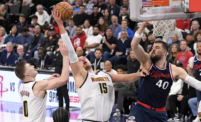 Denver Nuggets center Nikola Jokic, center, grabs a rebound away from Los Angeles Clippers center Ivica Zubac, right, as guard Christian Braun reaches during the second half in Game 6 of an NBA basketball first-round playoff series Thursday, May 1, 2025, in Inglewood, Calif. (AP Photo/Mark J. Terrill)