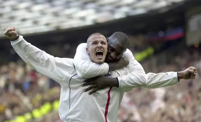 FILE - England's captain David Beckham, left, is congratulated by teammate Emile Heskey after scoring their second goal against Greece during their 2002 World Cup qualifying match at Old Trafford in Manchester, England, Saturday Oct. 6, 2001. (AP Photo/Adam Butler, File)
