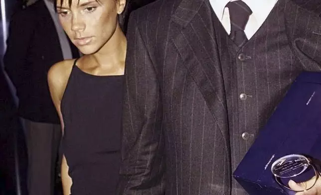FILE - English soccer player David Beckham of Manchester United, right, holds hands with his wife, Posh Spice Victoria Beckham, left, as they leave the UEFA Awards ceremony in Monaco on Aug. 26, 1999. (AP Photo/Michel Euler, File)