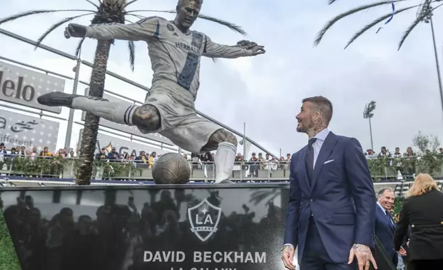 FILE - Former LA Galaxy MLS soccer midfielder David Beckham looks at a statue of himself at Legends Plaza in front of Dignity Health Sports Park in Carson, Calif., Saturday, March 2, 2019. (AP Photo/Ringo H.W. Chiu, File)