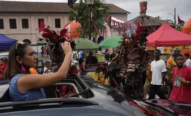 A visitor photographs revelers during the Devils and Congos Festival in Portobelo, Panama, Saturday, May 3, 2025. (AP Photo/Matias Delacroix)