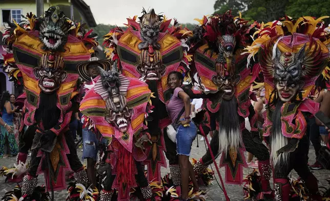 A woman poses with revelers during the Devils and Congos Festival in Portobelo, Panama, Saturday, May 3, 2025. (AP Photo/Matias Delacroix)