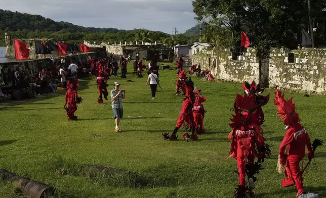 A visitor photographs revelers during the Devils and Congos Festival in Portobelo, Panama, Saturday, May 3, 2025. (AP Photo/Matias Delacroix)