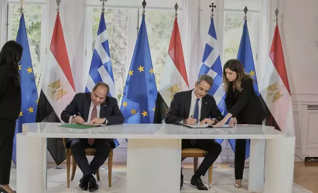 Greece's Prime Minister Kyriakos Mitsotakis, right, and the Egyptian President Abdel-Fattah el-Sissi sign bilateral agreements during their meeting in Athens, on Wednesday, May 7, 2025. (AP Photo/Petros Giannakouris)