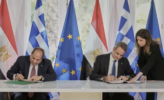 Greece's Prime Minister Kyriakos Mitsotakis, right, and the Egyptian President Abdel-Fattah el-Sissi sign bilateral agreements during their meeting in Athens, on Wednesday, May 7, 2025. (AP Photo/Petros Giannakouris)