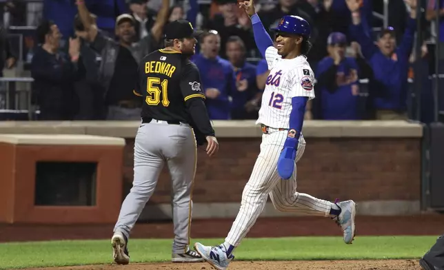 New York Mets' Francisco Lindor, right, scores during the ninth inning of a baseball game against the Pittsburgh Pirates Monday, May 12, 2025, in New York. (AP Photo/Pamela Smith)