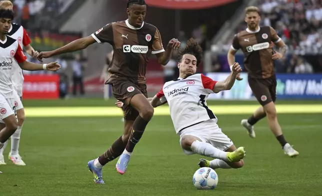 Frankfurt's Arthur Theate, right, and St. Pauli's Morgan Guilavogui, left, challenge for the ball during the German Bundesliga soccer match between Eintracht Frankfurt and FC St. Pauli in Frankfurt, Germany, Sunday, May 11, 2025. (Arne Dedert/dpa via AP)