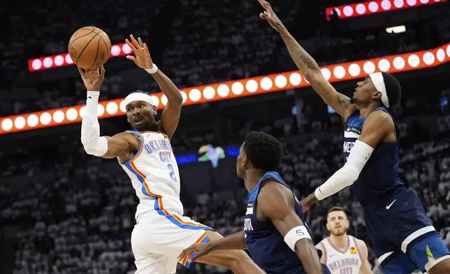 Oklahoma City Thunder guard Shai Gilgeous-Alexander (2) passes against Minnesota Timberwolves guard Anthony Edwards, center, and forward Jaden McDaniels, right, during the first half of Game 3 of the Western Conference finals of the NBA basketball playoffs, Saturday, May 24, 2025, in Minneapolis. (AP Photo/Abbie Parr)
