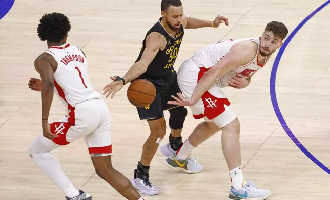 Houston Rockets center Alperen Sengun (28) passes to Rockets forward Amen Thompson (1) while guarded by Golden State Warriors guard Stephen Curry (30) in the fourth quarter of Game 6 of an NBA basketball first-round playoff series Friday, May 2, 2025, in San Francisco. (Santiago Mejia/San Francisco Chronicle via AP)