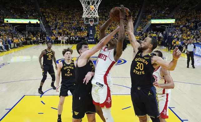 Houston Rockets forward Amen Thompson (1) shoots between Golden State Warriors center Quinten Post (21) and guard Stephen Curry (30) during the second half of Game 6 of an NBA basketball first-round playoff series Friday, May 2, 2025, in San Francisco. (AP Photo/Godofredo A. Vásquez)