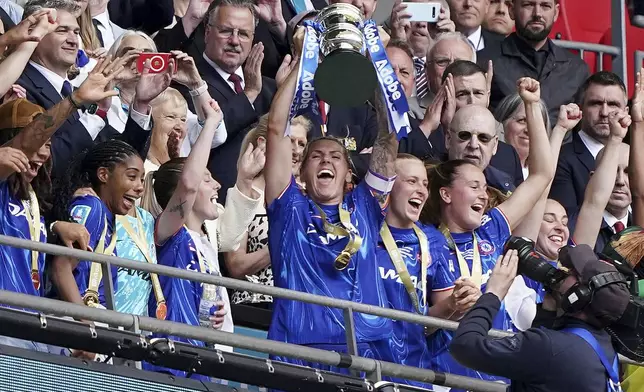 Chelsea's Millie Bright, center, lifts the trophy with teammates following victory in the English Women's FA Cup Final soccer match against Manchester United at Wembley Stadium, London, Sunday, May 18, 2025. (John Walton/PA via AP)