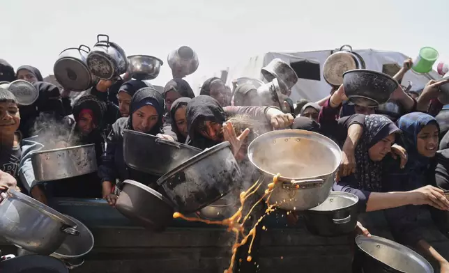 Palestinians struggle to get donated food at a community kitchen in Khan Younis, Gaza Strip, Monday, May 5, 2025. (AP Photo/Abdel Kareem Hana)