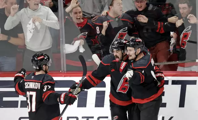 Carolina Hurricanes center Seth Jarvis, center, celebrates his goal with right wing Andrei Svechnikov (37) and defenseman Dmitry Orlov, right, after he scored against the Florida Panthers during the third period of Game 5 of the NHL hockey Stanley Cup Eastern Conference finals Wednesday, May 28, 2025, in Raleigh, N.C. (AP Photo/Chris Seward)