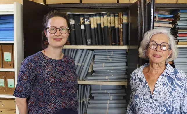 Rosa de Jong, left, and Lilly Duijm pose in front of the boxes of documents from the archive in Paramaribo, Suriname, Friday, May 2, 2025. (AP Photo/Oscar Keur)