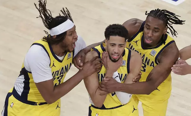 Indiana Pacers guard Tyrese Haliburton (0) is mobbed by teammates as he makes a choking motion after hitting a shot against the New York Knicks at the end of regulation to tie Game 1 of the NBA basketball Eastern Conference final, Wednesday, May 21, 2025, in New York. (AP Photo/Adam Hunger)