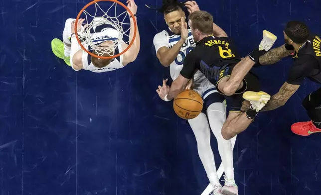 Golden State Warriors' Pat Spencer (61) goes head over heals on an offensive charge after colliding with Minnesota Timberwolves' Terrance Shannon (00) in the second half of Game 1 of an NBA basketball second-round playoff series, Tuesday, May 6, 2025, in Minneapolis. (Carlos Avila Gonzalez/San Francisco Chronicle via AP)