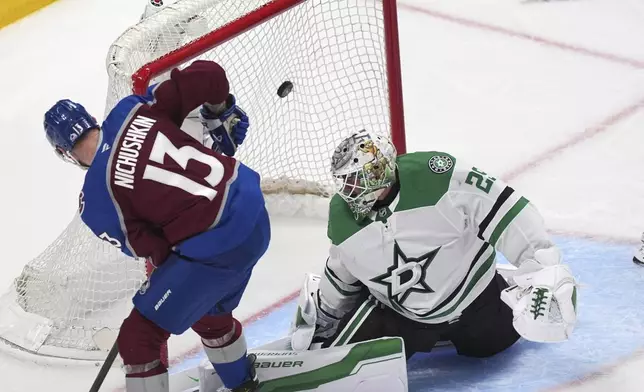 Colorado Avalanche right wing Valeri Nichushkin, front, flips the puck over Dallas Stars goaltender Jake Oettinger for a goal in the third period of Game 6 of an NHL first-round hockey playoff series Thursday, May 1, 2025, in Denver. (AP Photo/David Zalubowski)
