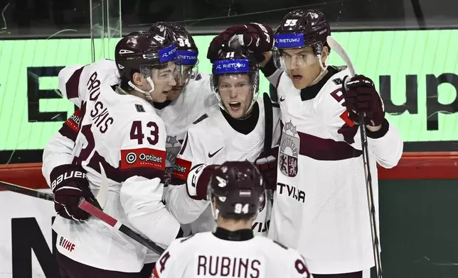 Latvia's Dans Locmelis, center, celebrates scoring with teammates Anri Ravinskis, from left, Eduards Tralmaks, Roberts Mamcics and Kristians Rubins during the IIHF Ice Hockey World Championship group A match between Slovenia and Latvia at Avicii Arena in Stockholm, Sweden, Tuesday May 13, 2025. (Anders Wiklund/TT News Agency via AP)