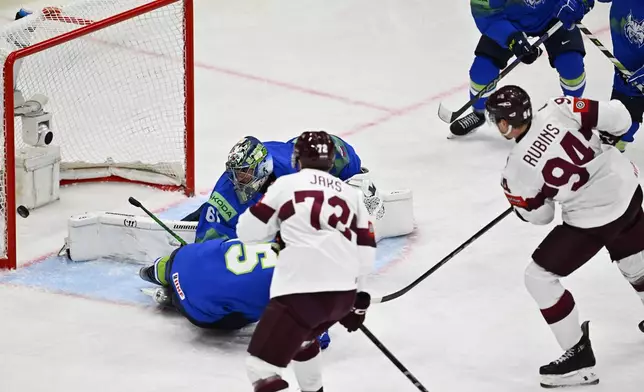 Latvia's Kristians Rubins, right, scores at Slovenia's goalkeeper Lukas Horak during the IIHF Ice Hockey World Championship group A match between Slovenia and Latvia at Avicii Arena in Stockholm, Sweden, Tuesday May 13, 2025. (Anders Wiklund/TT News Agency via AP)