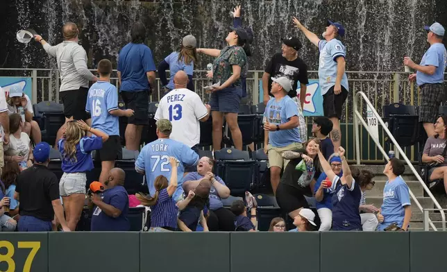 Fans watch a solo home run ball hit by Kansas City Royals' Bobby Witt Jr. during the first inning of a baseball game against the Detroit Tigers, Friday, May 30, 2025, in Kansas City, Mo. (AP Photo/Charlie Riedel)