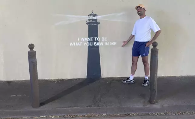 A man poses by an artwork by street artist Banksy, Friday, May 30, 2025 in Marseille, southern France. (AP Photo/Bishr Eltoni)