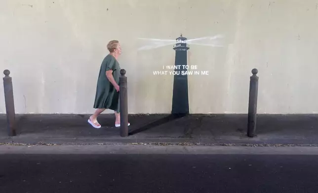 A woman walks past an artwork by street artist Banksy, Friday, May 30, 2025 in Marseille, southern France. (AP Photo/Bishr Eltoni)