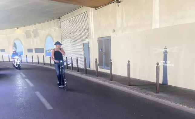 A man rides his scooter by an artwork by street artist Banksy, Friday, May 30, 2025 in Marseille, southern France. (AP Photo/Bishr Eltoni)