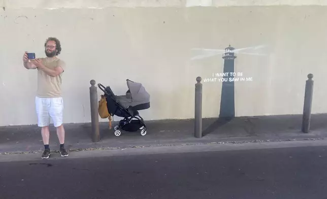 A man makes a selfie by an artwork by street artist Banksy, Friday, May 30, 2025 in Marseille, southern France. (AP Photo/Bishr Eltoni)