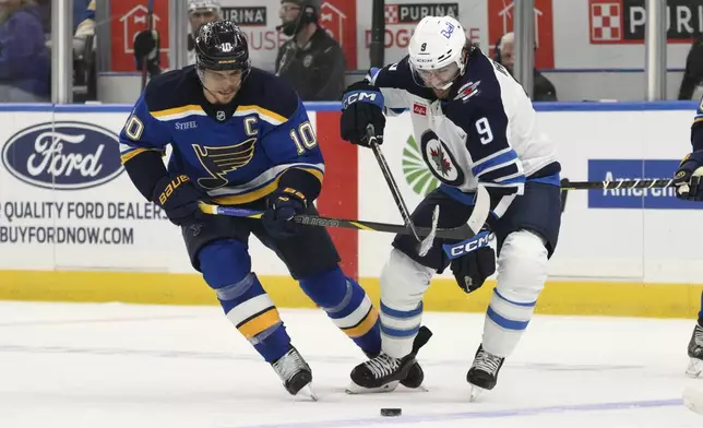 St. Louis Blues center Brayden Schenn, left, battles Winnipeg Jets left wing Alex Iafallo, right, during the first period in Game 6 of an NHL hockey first-round playoff series Friday, May 2, 2025, in St. Louis. (AP Photo/Jeff Le)