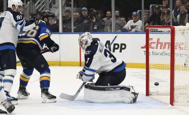 St. Louis Blues left wing Nathan Walker (26) and Winnipeg Jets center Cole Perfetti (91) look on as Jets goaltender Connor Hellebuyck gives up a goal during the second period in Game 6 of an NHL hockey first-round playoff series Friday, May 2, 2025, in St. Louis. (AP Photo/Jeff Le)