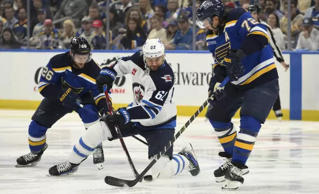 Winnipeg Jets right wing Nino Niederreiter (62) battles St. Louis Blues left wing Nathan Walker, left, and defenseman Justin Faulk, right, during the first period in Game 6 of an NHL hockey first-round playoff series Friday, May 2, 2025, in St. Louis. (AP Photo/Jeff Le)