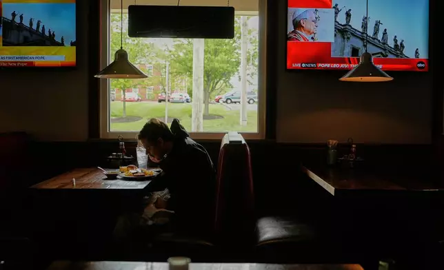 A patron eats lunch as live coverage of the newly elected Pope Leo XIV from St. Peter's Basilica at the Vatican is on televisions at Ron's Roost Chicken Restaurant, Thursday, May 8, 2025, in Cincinnati. (AP Photo/Carolyn Kaster)