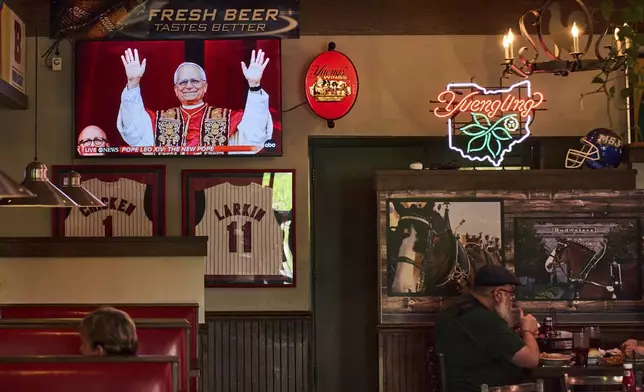 Patrons watch live coverage of the newly elected Pope Leo XIV from St. Peter's Basilica at the Vatican while having lunch at Ron's Roost Chicken Restaurant, Thursday, May 8, 2025, in Cincinnati. (AP Photo/Carolyn Kaster)