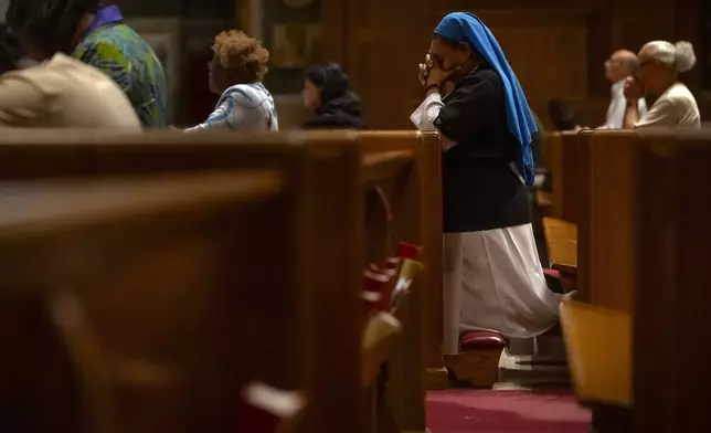 Members of the faithful pray during midday services at St. Matthew's Cathedral on Thursday, May 8, 2025, in Washington, after white smoke emanated from a chimney at the Vatican where 133 cardinals are gathering on the second day of a conclave to elect a successor to late Pope Francis. (AP Photo/Mark Schiefelbein)