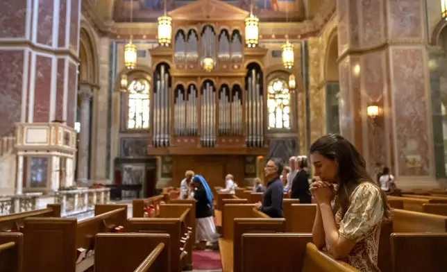 Members of the faithful pray during midday services at St. Matthew's Cathedral on Thursday, May 8, 2025, in Washington, after white smoke emanated from a chimney at the Vatican where 133 cardinals are gathering on the second day of a conclave to elect a successor to late Pope Francis. (AP Photo/Mark Schiefelbein)