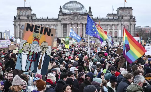 FILE - A protester holds a sign with a painted picture of Alice Weidel (AfD) and Friedrich Merz (CDU) with a burning Reichstag building and the inscription "No" during a demonstration in front of the Reichstag building in Berlin, Feb. 2, 2025. (Hannes P. Albert/dpa via AP)