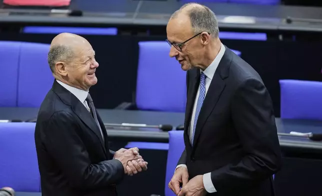 Friedrich Merz, right, talks to outgoing Chancellor Olaf Scholz at the German federal parliament, Bundestag, at the Reichstag building in Berlin, Tuesday, May 6, 2025. (AP Photo/Ebrahim Noroozi)