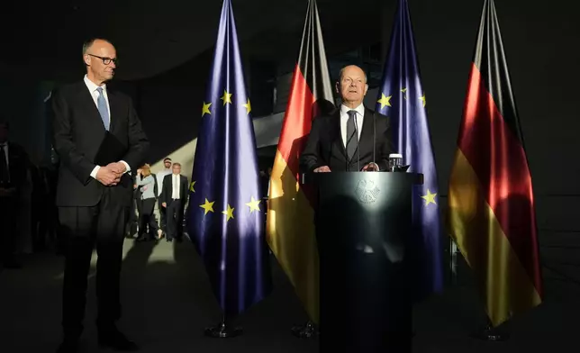 New elected German Chancellor Friedrich Merz, left, and former Chancellor Olaf Scholz, right, attend a handover ceremony in the chancellery in Berlin, Tuesday, May 6, 2025. (AP Photo/Ebrahim Noroozi)