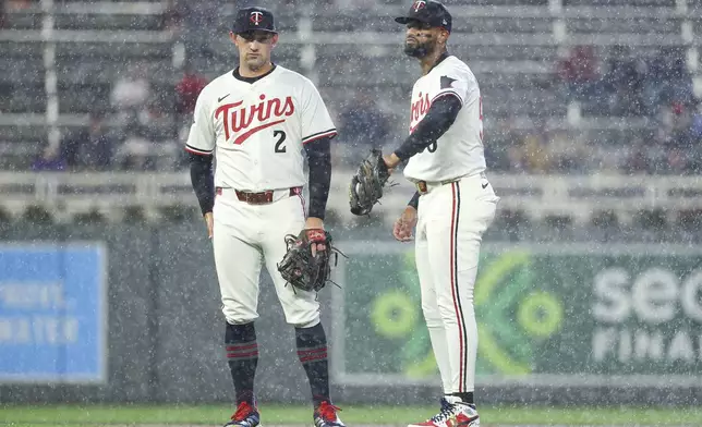 Minnesota Twins shortstop Brooks Lee, left, and second baseman Willi Castro, right, wait in the rain for the fourth inning of baseball game against the Cleveland Guardians, Monday, May 19, 2025, in Minneapolis. (AP Photo/Matt Krohn)