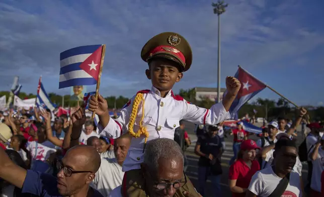 A boy dressed in a military uniform is carried on his grandfather's shoulders in the annual May Day parade at Revolution Square in Havana, Thursday, May 1, 2025. (AP Photo/Ramon Espinosa)