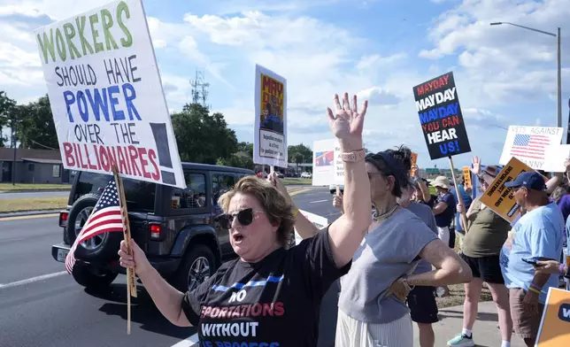 Demonstrators hold signs and wave to motorists in front of the Orange County Corrections Department during a May Day rally for worker and immigrant rights Thursday, May 1, 2025, in Orlando, Fla. (AP Photo/John Raoux)