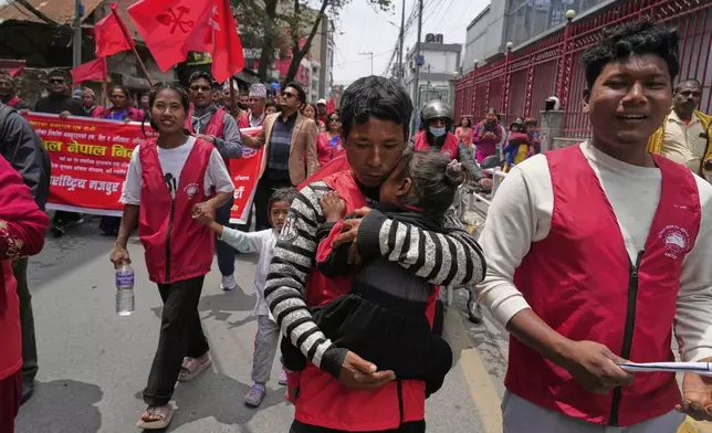 A worker affiliated with Communist Party of Nepal (Maoist Centre) carries his child during a May Day rally in Kathmandu, Nepal, Thursday, May 1, 2025. (AP Photo/Niranjan Shrestha)