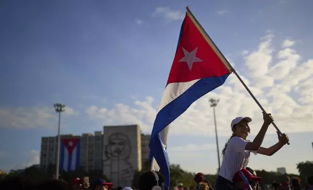A student waves a Cuban national flag during the May Day parade at Revolution Square in Havana, Thursday, May 1, 2025. (AP Photo/Ramon Espinosa)