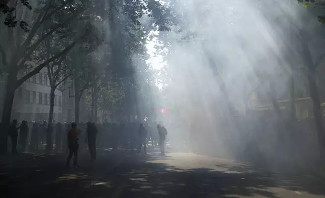 Protesters march through tear gas after incidents with police forces during the May Day demonstration, Thursday, May 1, 2025 in Paris. (AP Photo/Thibault Camus)